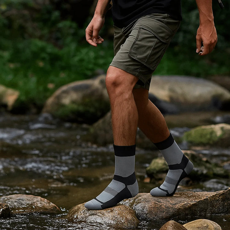 Walker stepping across river rocks in grey waterproof socks